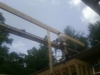 Carpenter setting a ridge beam over a new addition frame — Ice Dam Removal by Roofing Brothers in Lyndonville