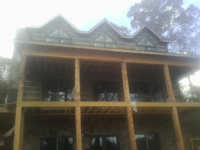 Dormers and porch framing on a large log home under construction — Roof Coating work by our crew in Lyndonville